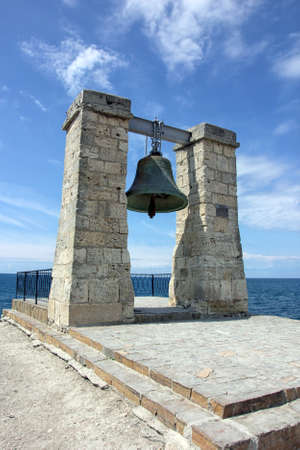 old large green bronze bell hanging on stone arch on the coast of Black sea in Crimeaの写真素材