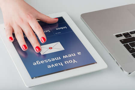 Woman s hand with red manicure opens a new email message on a tablet computer の写真素材