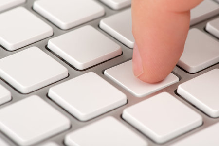 Close-up index finger is pressing an empty computer keyboard key with bokeh effect 