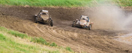 Competition. Buggy racing on a dirt road. Water splashing from the wheels.の写真素材