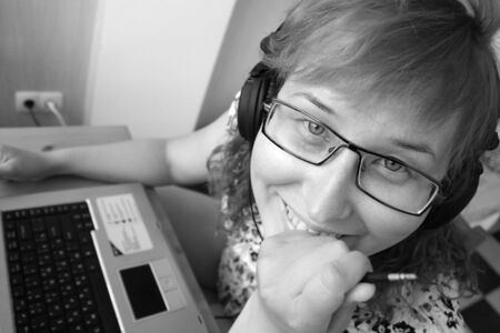 Switch off the music and start working! Smiling girl with laptop holding the plug from the headphones.の写真素材