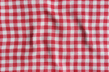 Red linen crumpled tablecloth. Texture of a red and white checkered picnic blanket.の写真素材