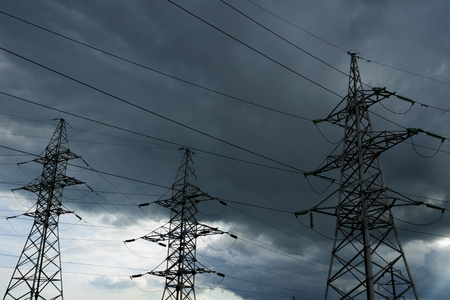 High voltage electricity pylons against thundercloud. Electric pole power lines and wires.の写真素材