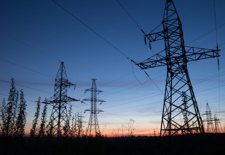 High voltage electricity pylons against sunset. Electric pole power lines and wires.