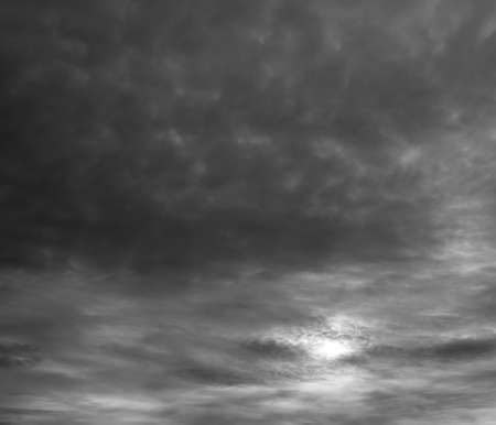 Dramatic gray clouds, sun shine through stormy clouds.の写真素材