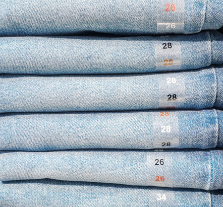 Photo of jeans in store. Stack of jeans on a shelf in a store.の写真素材