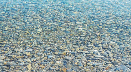 Photo of a calm transporent water surface with pebbles stone under water surfaceの写真素材
