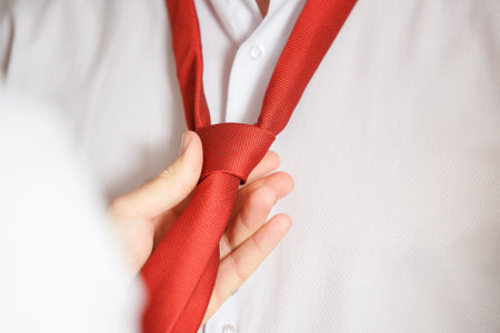 tying a red tie to a white shirt