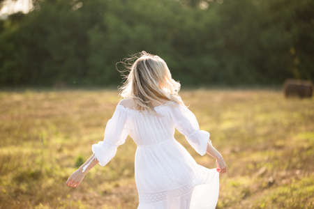 a girl in a white dress with flowing hair in the fieldの写真素材