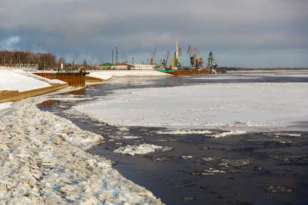 port cranes in the port against the backdrop of a frozen riverの写真素材