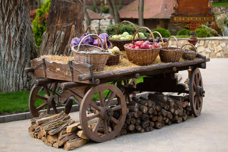 vintage cart on wooden wheels with baskets of vegetables and fruitsの写真素材