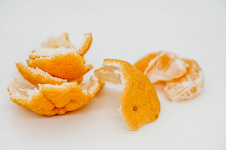 Slices of juicy tangerine disassembled into pieces close-up. They lie on a light surface. Side view