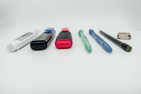 Set of markers and pens on a white table close-up. Pens and markers lie on a light surface. Side viewの写真素材