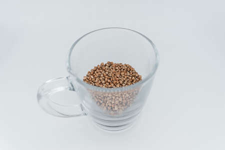 Buckwheat in a transparent glass on a white background. Side viewの写真素材