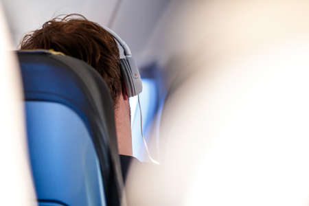 Man listening to the music in the headphones in the planeの写真素材