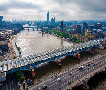 Modern Blackfriars station with solar roof spans River Thames, surrounded by London landmarks including St. Paul's and city skyscrapers; ideal for travel and infrastructure themesの写真素材