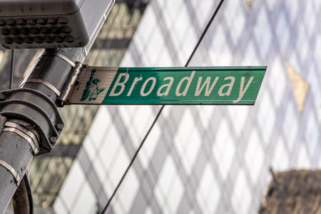 Detailed view of the Broadway street sign in Manhattan with modern glass building in background. Represents culture, entertainment, tourism, travel, lifestyle, and iconic NYC landmarksの写真素材