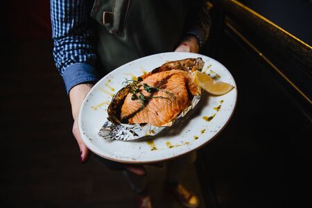 Juicy baked fish steak lies on a round plate.の写真素材