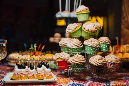 Freshly made chocolate cupcakes, decorated with cream and colored balls, stand on a stand. Holiday atmosphere, mouth-watering dessert . Candy bar.の写真素材