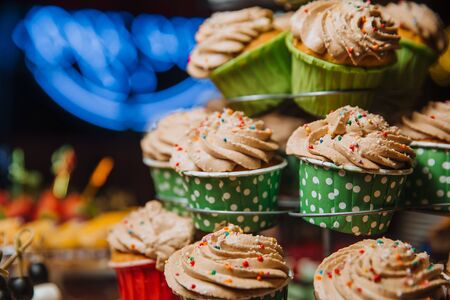 Freshly made chocolate cupcakes, decorated with cream and colored balls, stand on a stand. Holiday atmosphere, mouth-watering dessert . Candy bar.の写真素材