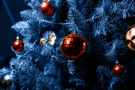 The beautiful Christmas tree is decorated with red balls, gold bows and garlands. Close-up photo. The main color of the Year 2020.の写真素材