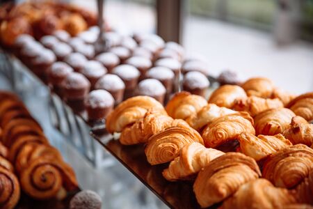 Pastries, croissants and muffins lie on the glass table.の写真素材
