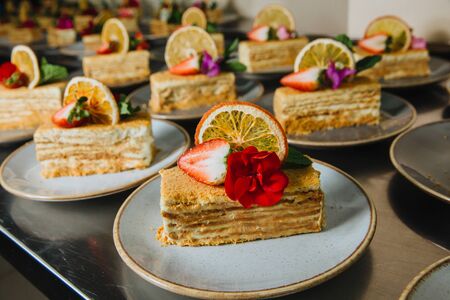 Delicious slices of honey cake served with fresh strawberries and fresh flower on a plate ready to serve.の写真素材