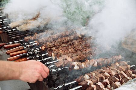 The cook prepares meat-kebab, cut into pieces, barbecue. The meat is strung on many skewers.の写真素材