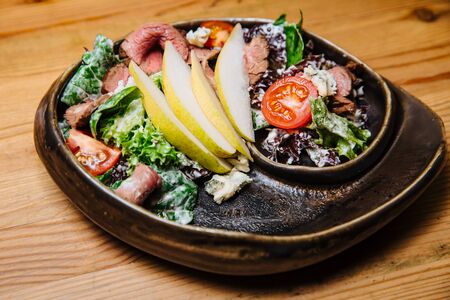 Sliced grilled barbecue meat with salad of greens, tomatoes and pears.Healthy food.の写真素材