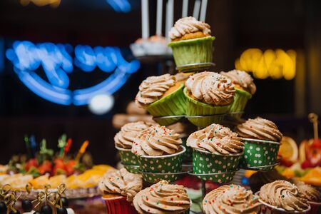 Freshly made chocolate cupcakes, decorated with cream and colored balls, stand on a stand. Holiday atmosphere, mouth-watering dessert . Candy bar.の写真素材