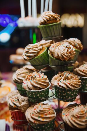Freshly made chocolate cupcakes, decorated with cream and colored balls, stand on a stand. Holiday atmosphere, mouth-watering dessert . Candy bar.の写真素材