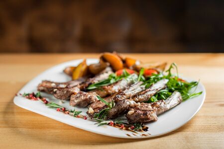 Juicy grilled ribs, cooked with vegetables and rosemary, lie on a white plate .の写真素材