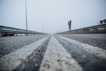 The dividing line on the road is white the view from below on the road paved going. Road markings on asphalt on the street.の写真素材