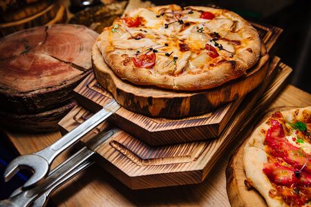 A hot pizza, ready to be served, lies on a wooden pizza board.の写真素材