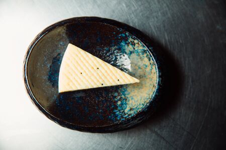 A piece of blue cheese lies on a plate.の写真素材