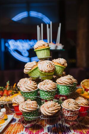 Freshly made chocolate cupcakes, decorated with cream and colored balls, stand on a stand. Holiday atmosphere, mouth-watering dessert . Candy bar.の写真素材
