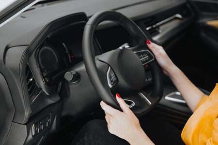 Female hands on the steering wheel of a car while driving. の写真素材