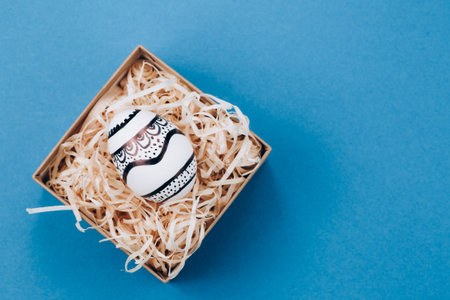 The Easter egg is painted in black and white, an abstraction, lies in a box.