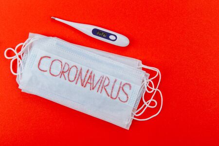 Protective medical mask with the inscription coronavirus on a red background.の写真素材