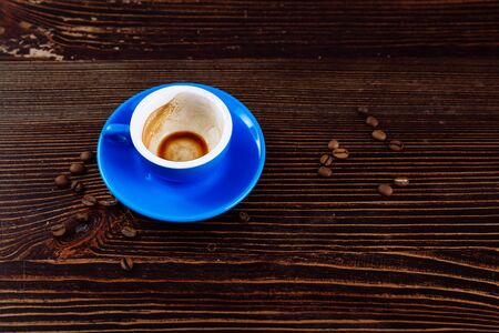 Dirty blue cup after coffee on a wooden table. Near to the cup are coffee beans. の写真素材
