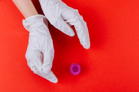 Hands in white medical gloves near an abstract viral model of coronavirus.の写真素材