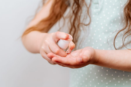 The child uses a hand sanitizer. Hygiene concept. Prevent the spread of germs and bacteria and avoid...