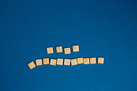 Inscription Stop Coronavirus on wooden cubes on a blue background. Health concept.