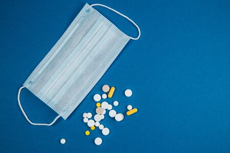 Medical face mask and pills to protect from Coronavirus on blue background. The concept of protecting health from the virus. Copy spaceの写真素材