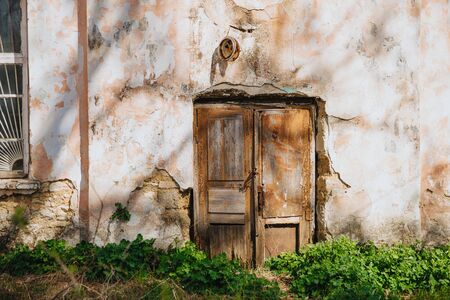 Old wooden door on a weathered and collapsing wall.の写真素材