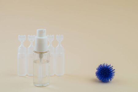 Abstract model of coronavirus, ampoule with medicine and bottle with antibacterial gel for hands on a beige background. Hygiene concept.の写真素材