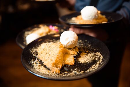 Crispy pastry dessert, melted cheese inside and sprinkled with crushed pistachios. Dessert served with a scoop of white ice cream.の写真素材