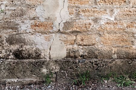 Rough texture of a brick wall made of shells. There is a crack in the middle of the wall.の写真素材