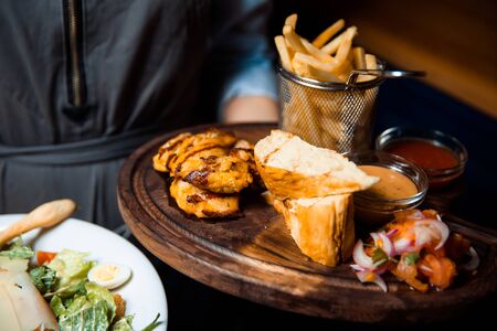 Barbecue chicken wings with two sauces. Served with french fries, tomato and onion salad and crispy slices of bread.の写真素材