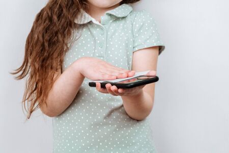 The child disinfects the phone screen to prevent coronavirus .の写真素材